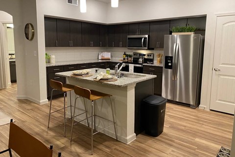 a kitchen with a center island and a stainless steel refrigerator of Avery Oaks in Austin, TX